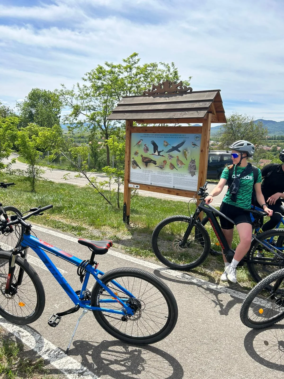 A group of cyclists by a biodiversity info board