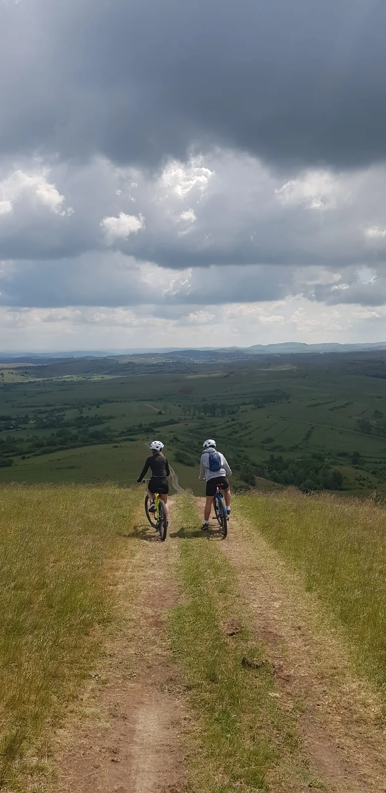 Two cyclists riding down a hill with a wide view